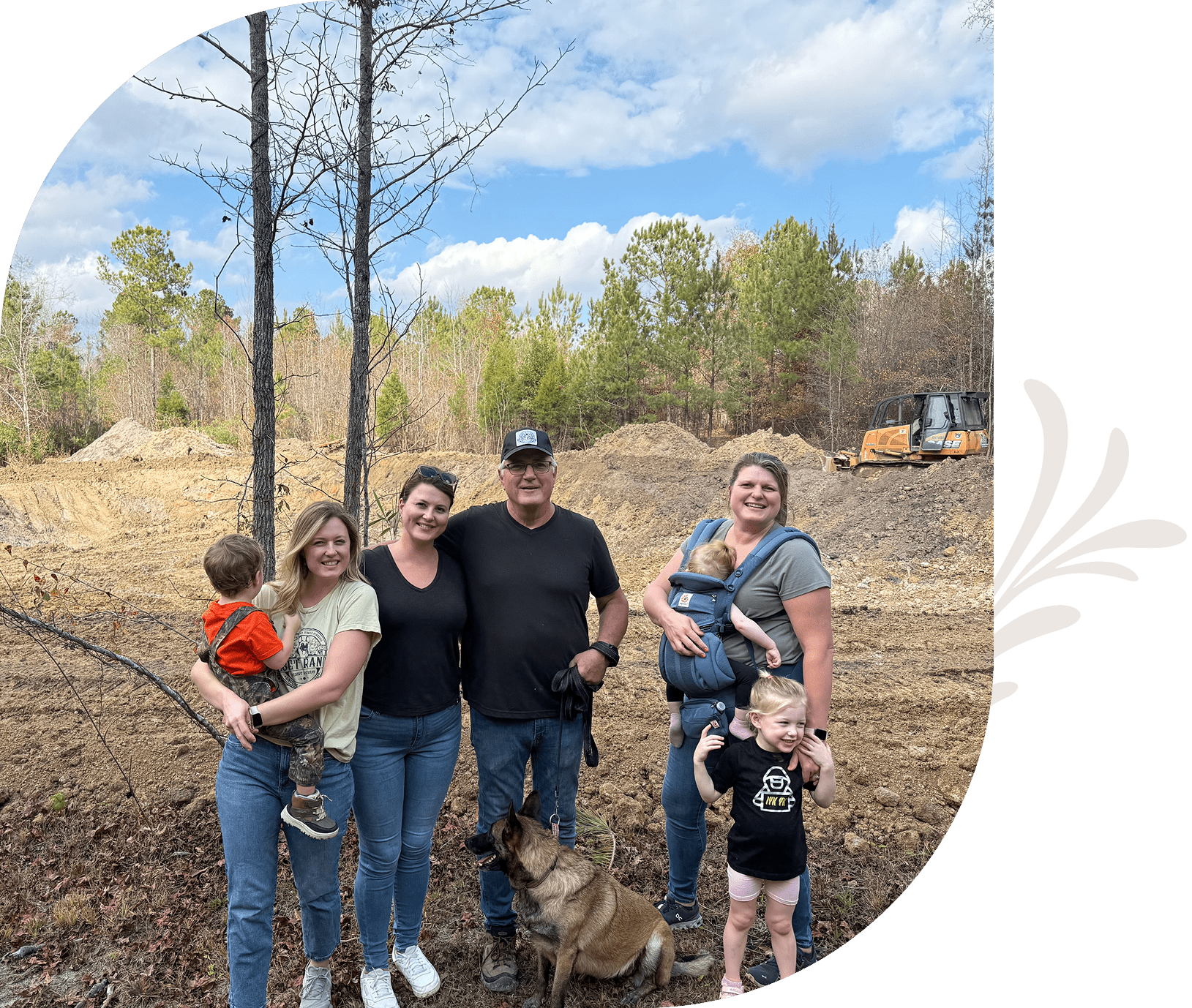 Family posing outdoors with trees and sky.