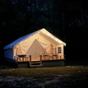 Cozy illuminated cabin tent glowing at night in the forest.