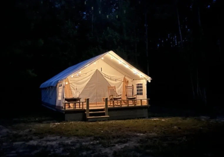 Cozy illuminated cabin tent glowing at night in the forest.